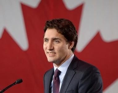 Justin Trudeau w swobodnej pozie, angażujący się z obywatelami, na tle tłumu lub kanadyjskiego krajobrazu.