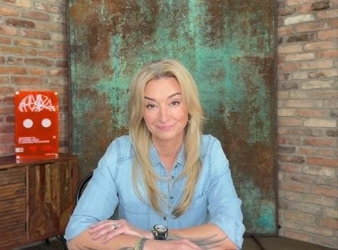Martyna Wojciechowska w swoim domu w Warszawie, w swobodnej pozie, z subtelnymi elementami podróżniczymi w tle.