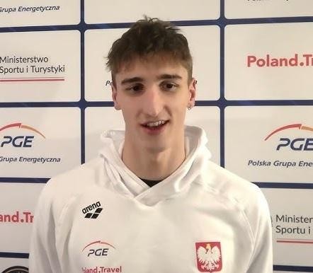 Ksawery Masiuk trenujący stylem grzbietowym w basenie w Teksasie, z widokiem na charakterystyczny krajobraz.