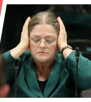 Krystyna Pawłowicz podczas wystąpienia publicznego, z ekspresywną mimiką i gestykulacją, podkreślającą jej charakterystyczny sposób komunikacji.