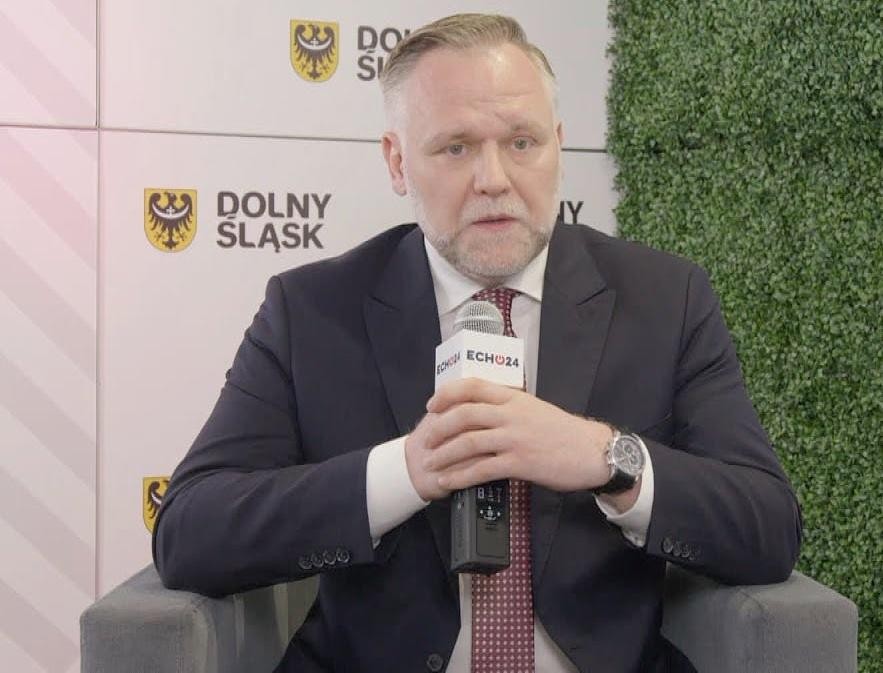 Dawid Jackiewicz przemawiający na wiecu politycznym, z pasją i determinacją, na tle sugerującym dużą publiczność.