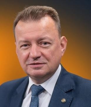 Mariusz Błaszczak jako minister obrony narodowej podczas inspekcji wojskowej, symbolizujący jego zaangażowanie w kwestie bezpieczeństwa i obronności kraju.