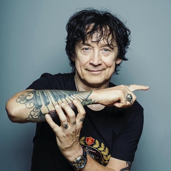 Dłonie Jana Borysewicza grające na gitarze, zbliżenie na technikę i pasję.