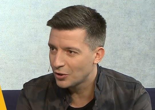 Portret Michała Cessanisa, polskiego dziennikarza i podróżnika, z ciepłym uśmiechem, symbolizujący jego profesjonalizm i pasję do opowiadania historii.