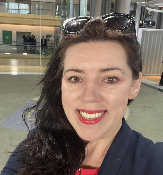 Dominika Ćosić w profesjonalnym otoczeniu, prowadząca dyskusję, symbolizująca jej aktywność w mediach międzynarodowych.