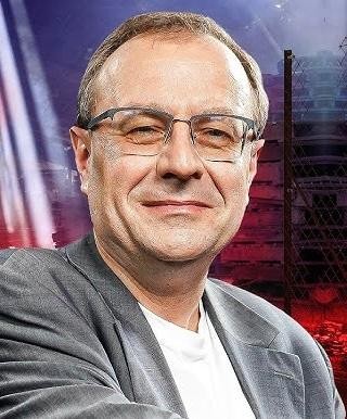 Antoni Dudek podczas wykładu lub wystąpienia publicznego, z ożywioną mimiką i gestykulacją, prezentujący swoją wiedzę.