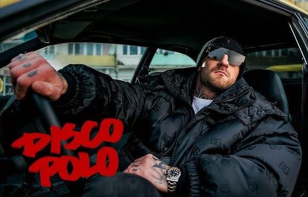 Kizo (Patryk Woziński) w studiu nagraniowym, w słuchawkach, skupiony na mikrofonie.